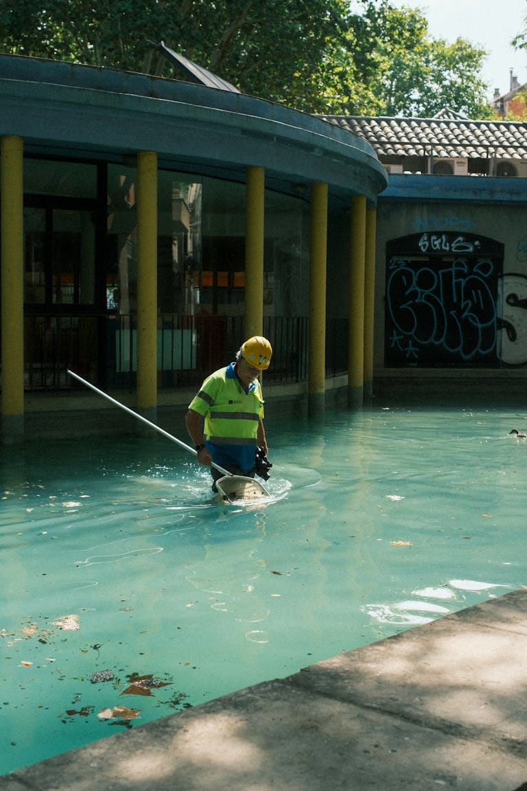 How to Find the Best Pool Cleaning Service Near Me in the USA How to Find the Best Pool Cleaning Service Near Me in the USA, A pool maintenance worker wearing safety gear cleans an outdoor pool in Barcelona, Spain.