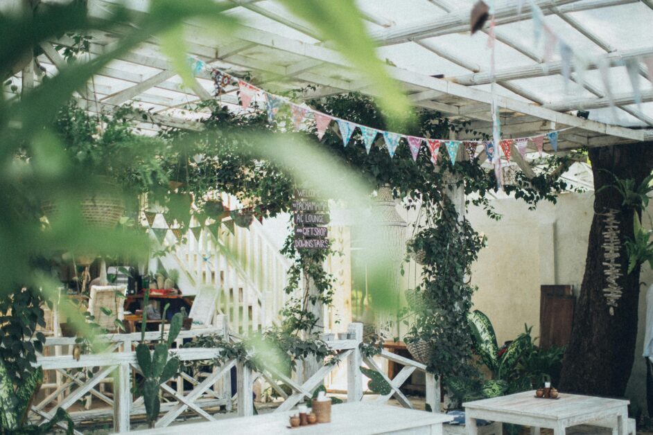 A cozy outdoor patio adorned with greenery, colorful pennants, and rustic furniture, perfect for relaxation.